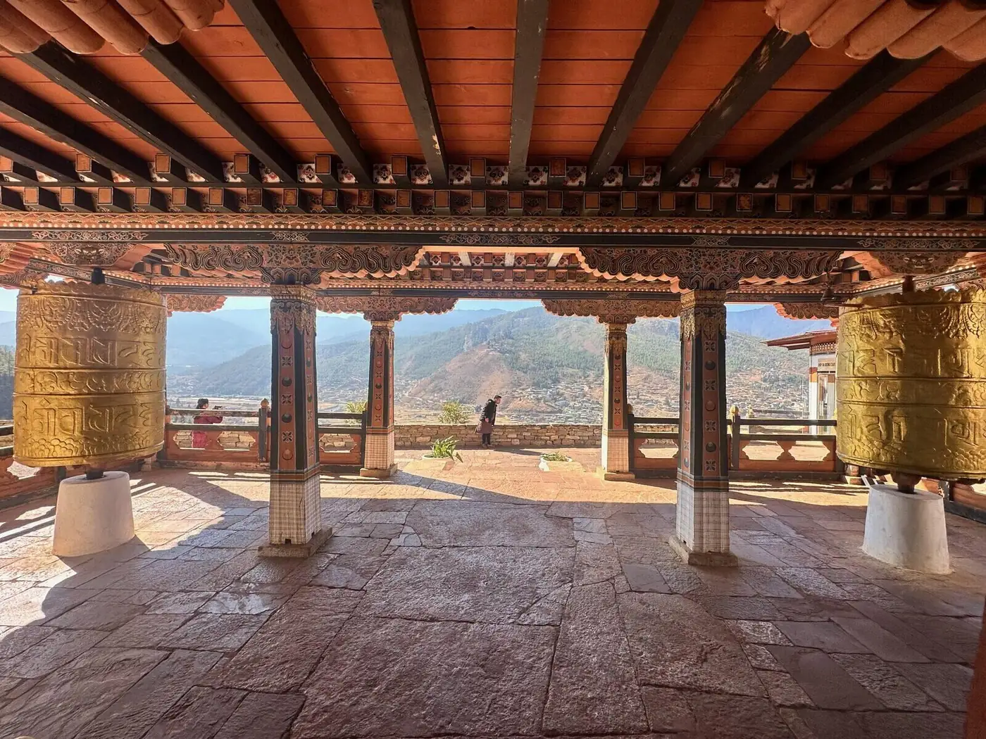 Covered terrace with golden prayer wheels above the Paro Valley