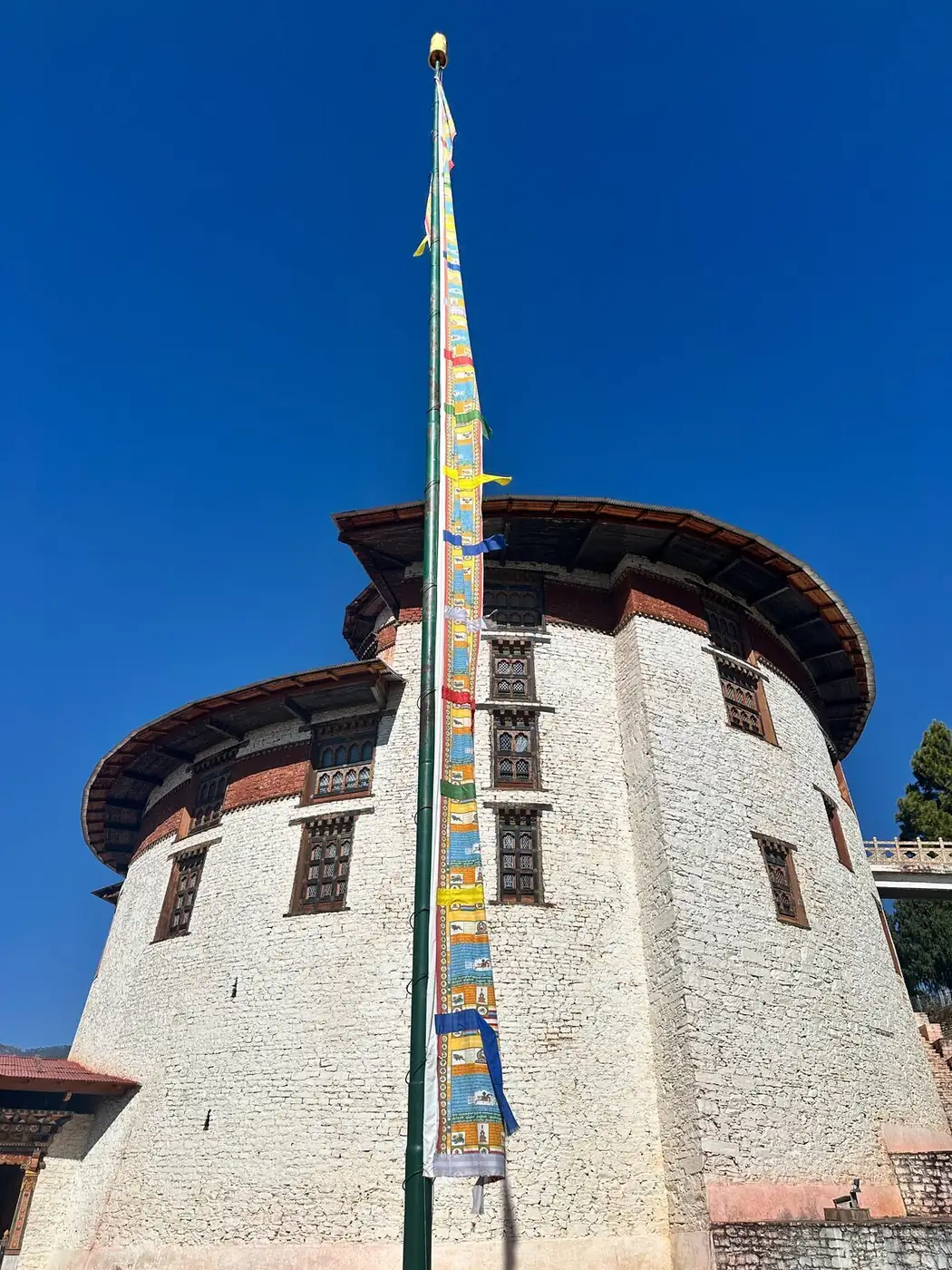 Ta Dzong watchtower above Paro with prayer-flag pole